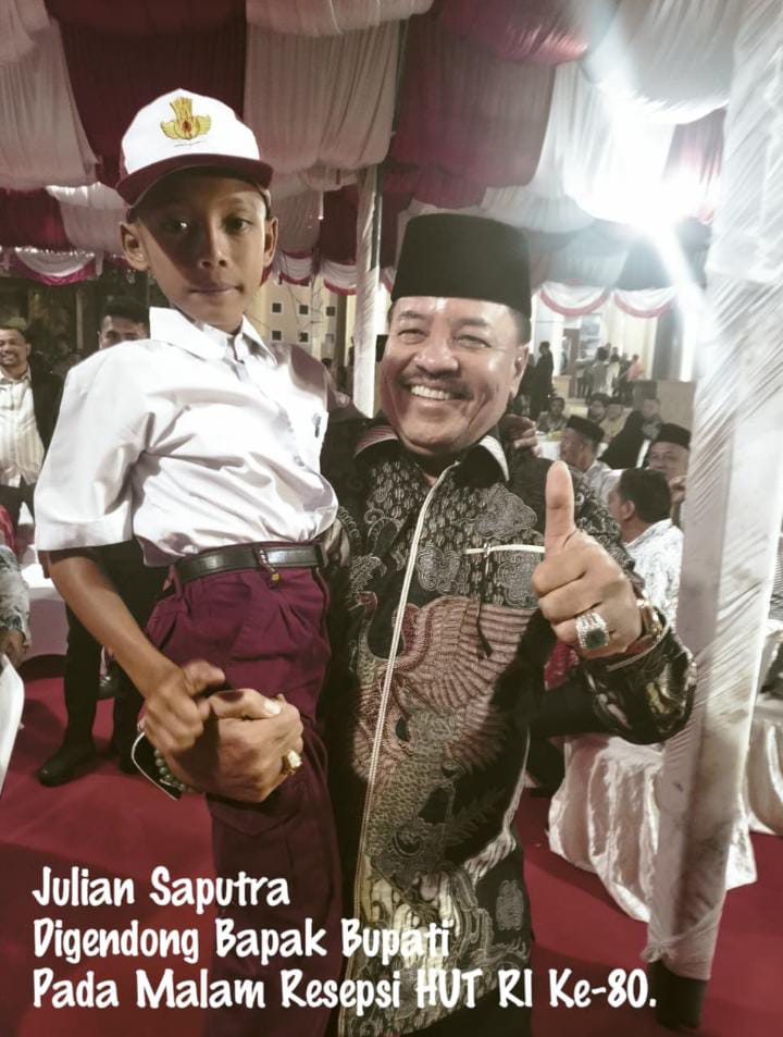Bupati Nagan Raya DR. Teuku Raja Keumangan.SH.MM Gendong Julian Saputra dengan sapaan akrab Bulek yang berani memanjat tebing tiang Bendera